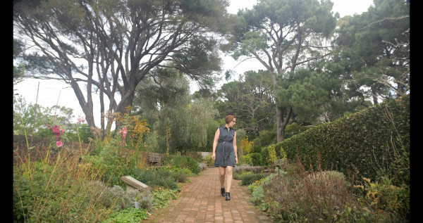 Image shows Cynthia walking down a garden path.