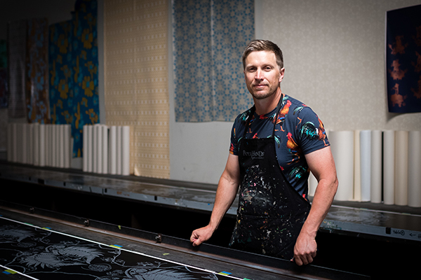 Image shows Ben Masters standing at a work bench